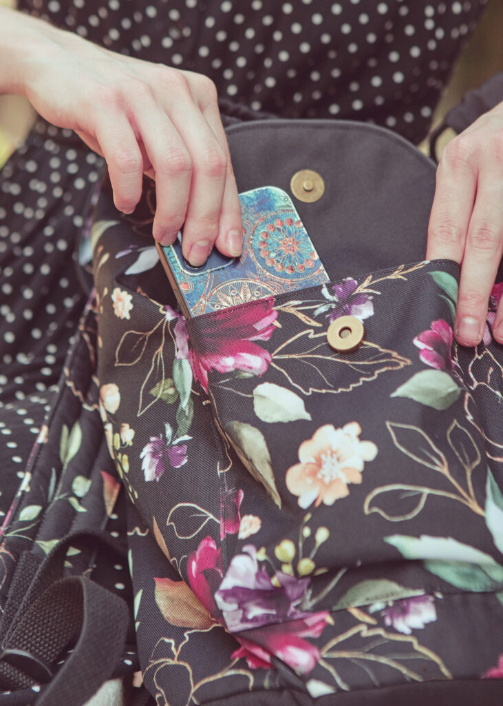 Modrý mobilní telefon vyčnívající z dámského květovaného batohu ELLIE Od Klárky